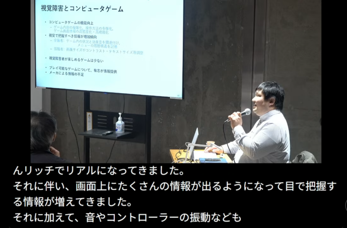 ライブ配信画面の様子。松尾先生とプレゼン投影モニターが映る映像が画面上部に、字幕が4行で画面下部に表示されている。