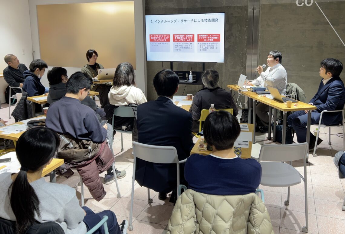 会場内の様子。中央にプレゼン提示のモニター 左に近貞氏、謝氏、右側に松尾先生、垣野内先生が座っている。